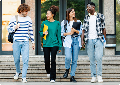 Vier junge Erwachsene gehen lachend vor einem Gebäude die Treppe hinunter.