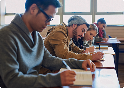 Studierende sitzen in einem Klassenzimmer und machen Notizen.